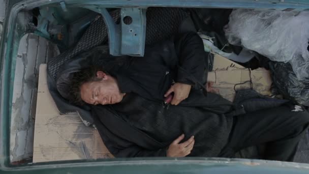 Бездомний чоловік спить у машині без даху — стокове відео