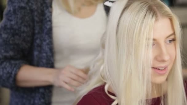 Un peluquero profesional hace el peinado de la chica, chica rubia — Vídeo de stock