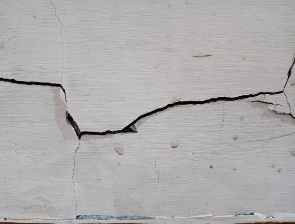 Beyaz bir duvardaki önemli yapısal çatlakların soyut dokusu.