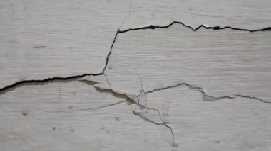 Beyaz bir duvardaki önemli yapısal çatlakların soyut dokusu.