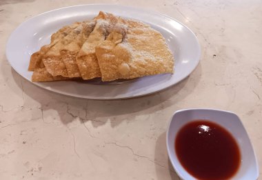 Endonezya Çin mutfağı, içi tatlı ve lezzetli tavuk etiyle dolu kızarmış hamur köfteleri beyaz tabakta mermer masada domates sosuyla servis ediliyor..