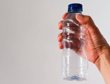Beyaz arka planda izole edilmiş mavi başlıklı boş plastik su şişesini tutan kadın. Metin için alanı kopyala.