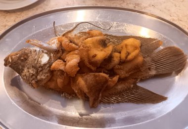 Gurame Goreng 'in ya da Sundan mutfağında gümüş tabakta servis edilen geleneksel bir Endonezya yemeği olan kızarmış gourami' nin yakın çekimi..