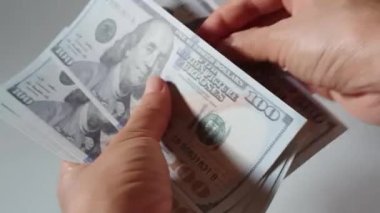 Beyaz arka planda izole edilmiş 100 dolarlık banknotları sayan bir kadın. Ticari ticaret finansal tasarruf kavramı.