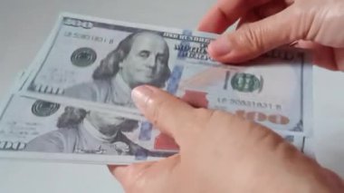 Beyaz arka planda izole edilmiş 100 dolarlık banknotları sayan bir kadın. Ticari ticaret finansal tasarruf kavramı.