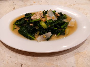 Kailan, Çin brokolisi ya da tavukla kızartılmış Çin lahanası olarak da bilinir ve mermer masada izole edilmiş beyaz tabakta lezzetli bir sos..