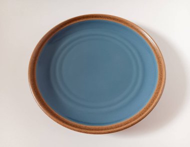 Mavi yemek takımının, beyaz arka planda kahverengi benekli kenarlı taş kaplama görüntüsünü kapat..