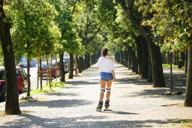 Tekerlekli paten parkta sürme kısa kot şortlu genç atlet