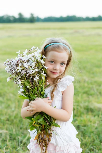 Retrato bonito menina com flores no prado — Fotografia de Stock