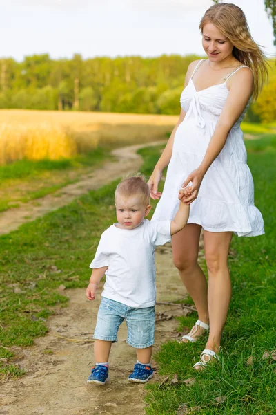 Pregnant mom with a boy resting in a meadow. — Stock Photo, Image