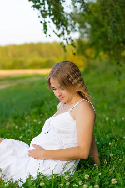 草の上に座って妊娠中の女性の肖像画 — ストック写真