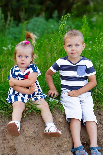 Мальчик и девочка летом сидят на траве на открытом воздухе — стоковое фото
