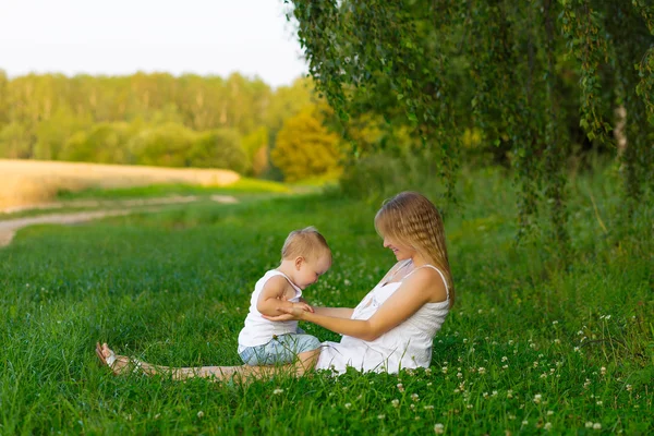 Embarazada mamá con un niño descansando en un prado . —  Fotos de Stock