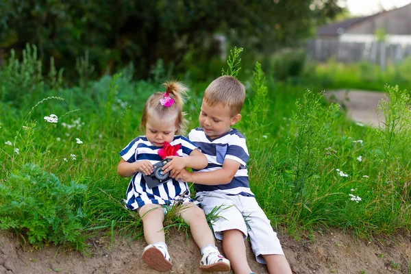 小男孩和女孩坐在户外草地上的相机 — 图库照片