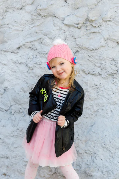 Little happy girl near textured concrete wall — Stock Photo, Image