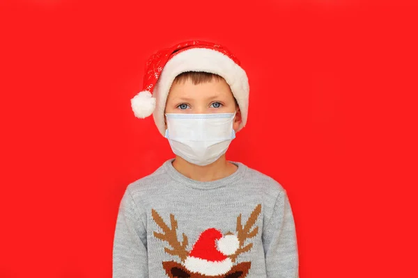 Αγόρι που φοράει αναπνευστική μάσκα και πουλόβερ της Πρωτοχρονιάς σε κόκκινο φόντο. — Φωτογραφία Αρχείου