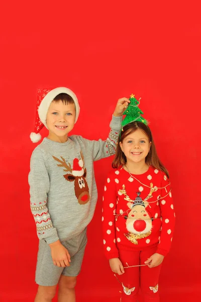 Pojke och flicka i nyår tröjor på en röd bakgrund. — Stockfoto