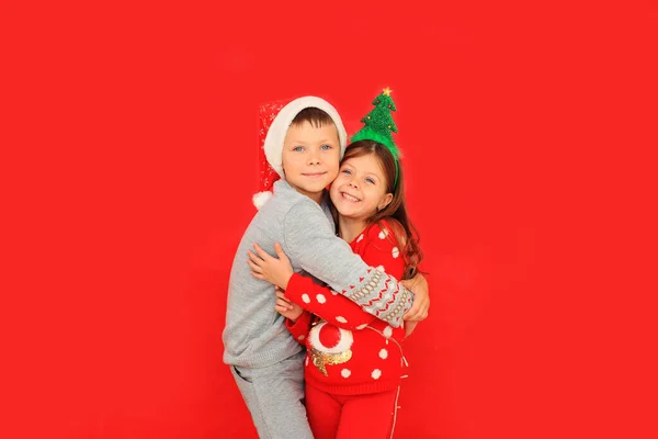 Boy and girl in New Years sweaters on a red background. — Stock Photo, Image