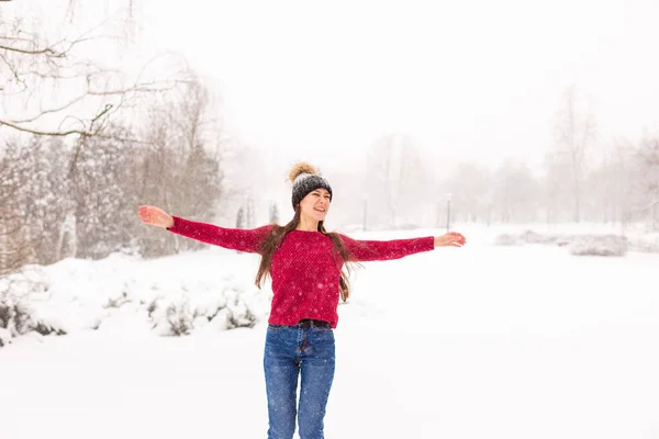 Chica de rojo en un parque nevado en invierno cuando nieva. — Foto de Stock