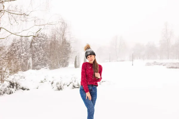 Girl in red in a snowy park in winter when it snows. — Stock Photo, Image