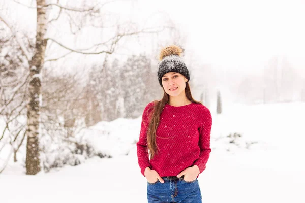 Дівчина в червоному в сніжному парку взимку, коли йде сніг . — стокове фото