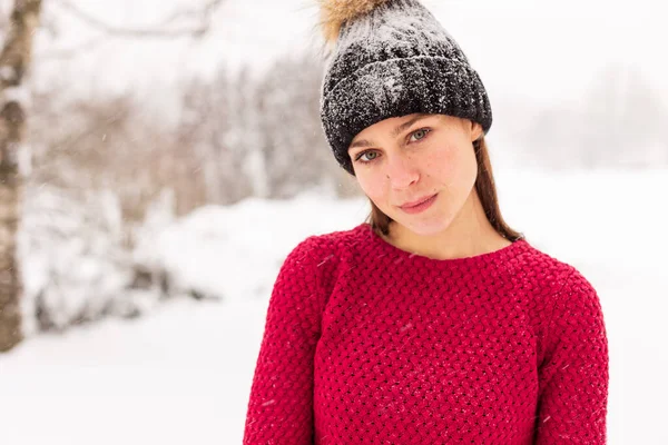 Girl in red in a snowy park in winter when it snows. — Stock Photo, Image