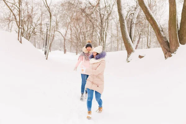 Dos niñas juegan bolas de nieve en el invierno en el bosque. — Foto de Stock