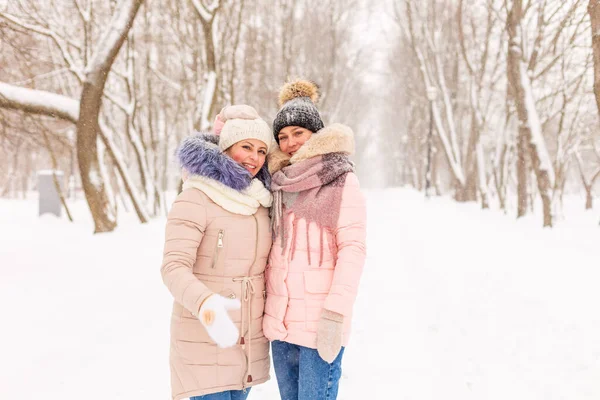 Дві дівчини гуляють в зимовому парку на снігу . — стокове фото