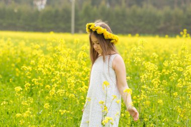 Çiçek açan bir tarlada sarı çiçekli bir çocuk.
