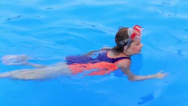 Ein Kind in Badeanzug und Wassermaske schwimmt im Pool des Wasserparks. — Stockvideo