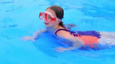 Mayolu ve su maskeli bir çocuk su parkının havuzunda yüzer..