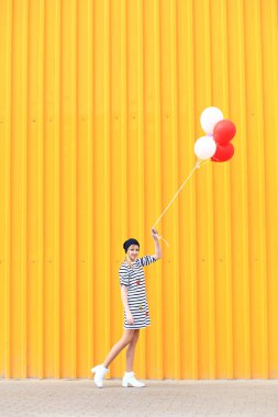 Elinde kırmızı ve beyaz balonlar olan bir kız