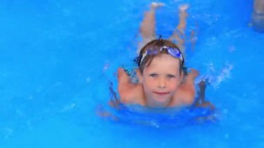 Mayolu ve su maskeli bir çocuk su parkının havuzunda yüzer..