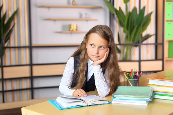 Школярка сидить над блокнотами. Дівчина пише в шкільному записнику . — стокове фото