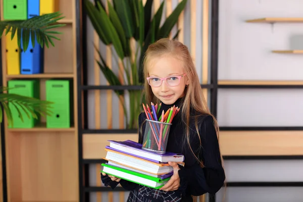 Retrato de uma menina de uniforme escolar com um livro nas mãos. — Fotografia de Stock
