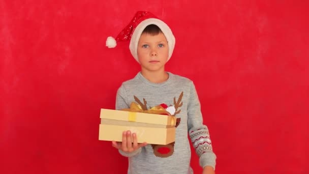Niño en un suéter de Año Nuevo sobre un fondo rojo. — Vídeo de stock