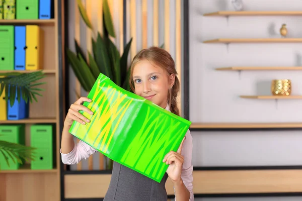 Retrato de uma menina de uniforme escolar com um livro nas mãos. — Fotografia de Stock