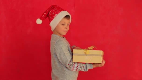 Fiú újévi pulóverben, piros háttérrel. — Stock videók