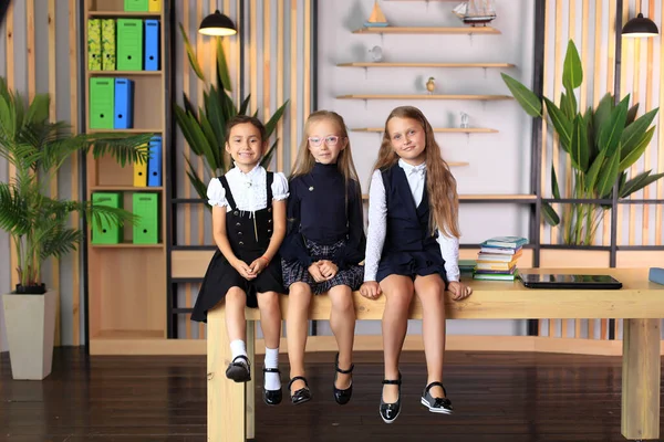 Jovens estudantes em uniformes escolares antes da aula em sala de aula. — Fotografia de Stock