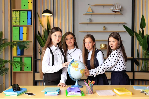 Kinder in Schuluniformen mit einer Weltkugel im Büro. — Stockfoto