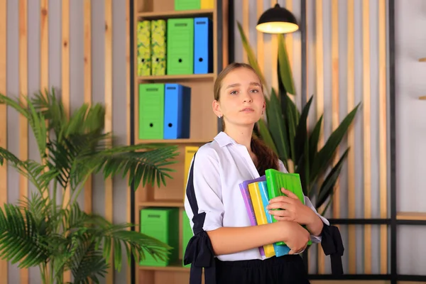 Retrato de uma menina de uniforme escolar com um livro nas mãos. — Fotografia de Stock