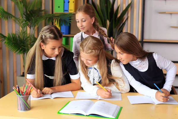 Una giovane studentessa in uniforme scolastica scrive in un quaderno. — Foto Stock