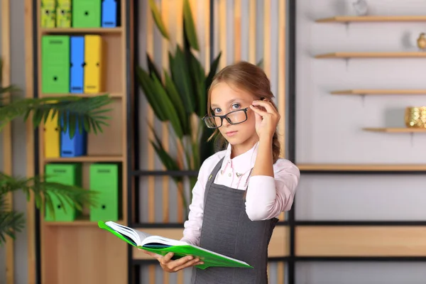 Retrato de uma menina de uniforme escolar com um livro nas mãos. — Fotografia de Stock