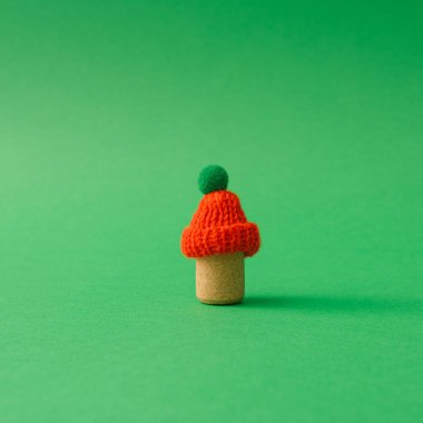 Asgari Noel kompozisyonu, mantar ve yeşil arka planda örülmüş şapka. Basit kış hala sıcak tonlarda. Minimum tatil kişiliği, sıcaklık ve kış cazibesi.