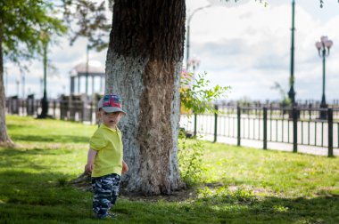 Mutlu küçük çocuk bir ağaç Park yakınında duran.