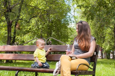 Küçük çocuk annesi ile bir tezgah ve içecek su üzerinde oturur.