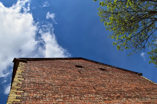 石、れんが造りの建物、青い空の雲のシールド — ストック写真