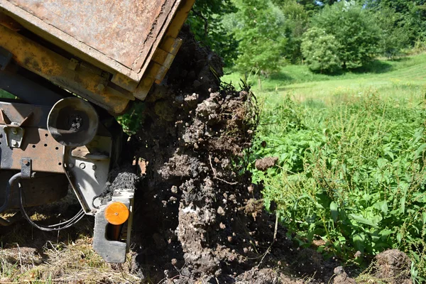 Vrachtwagen dumpt natte modder uit een emmer — Stockfoto