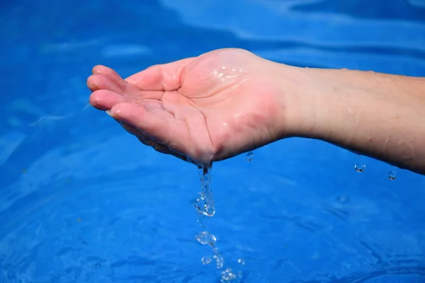 Ovanför poolen från en mänsklig hand strömmande vatten — Stockfoto