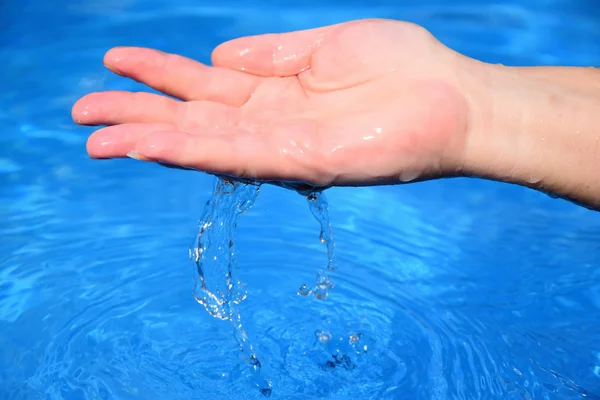 Mão humana com água clara no fundo azul — Fotografia de Stock